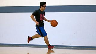 A student is dribbling a basketball on the NMT practice court.